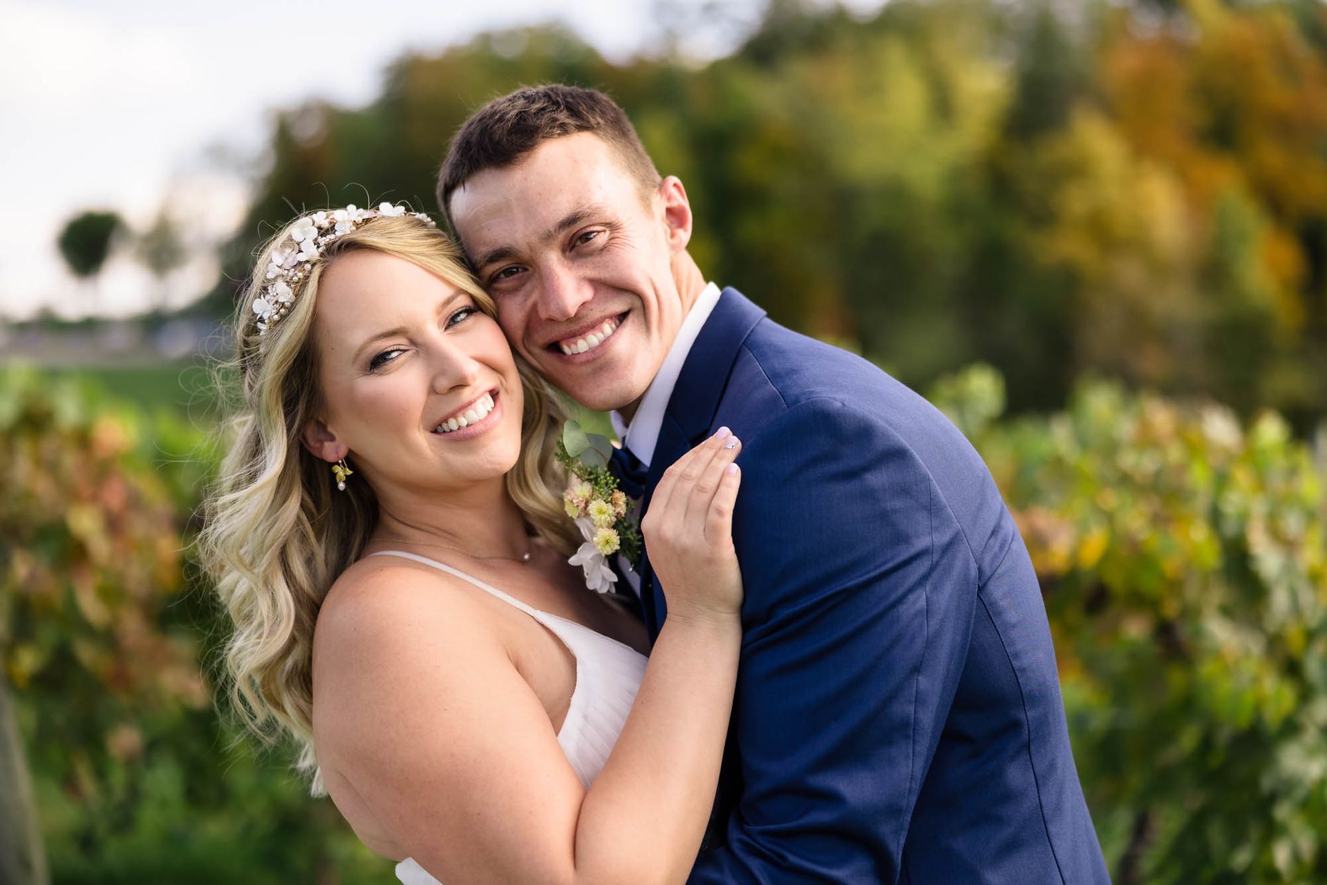 A bride and groom are posing for a picture in a vineyard.