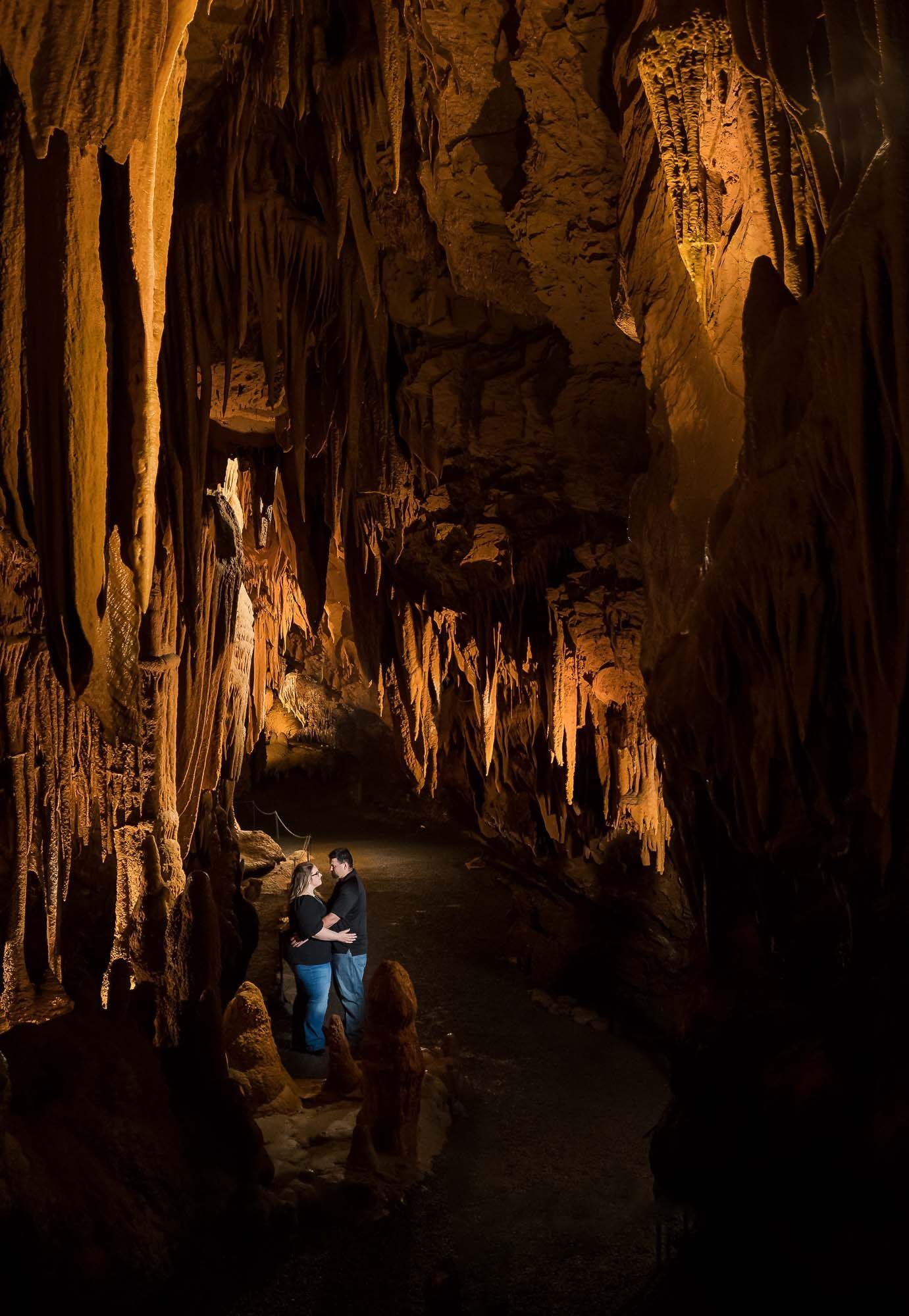 A couple is standing in a cave with a light shining on them.