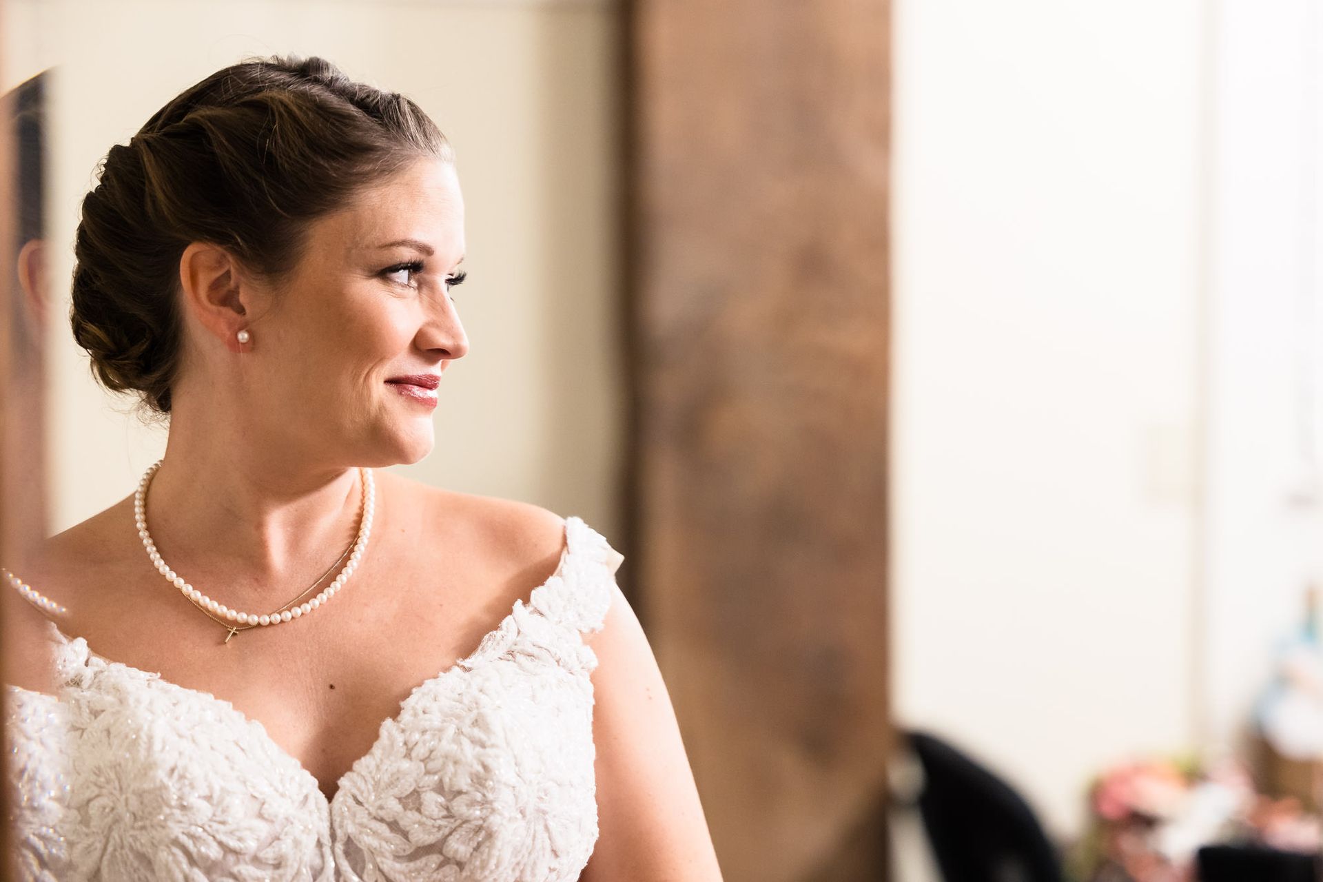 A bride in a wedding dress is looking at herself in the mirror.