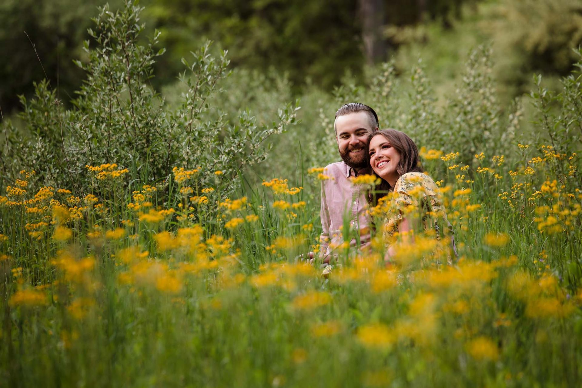 A man and a woman are sitting in a field of yellow flowers.