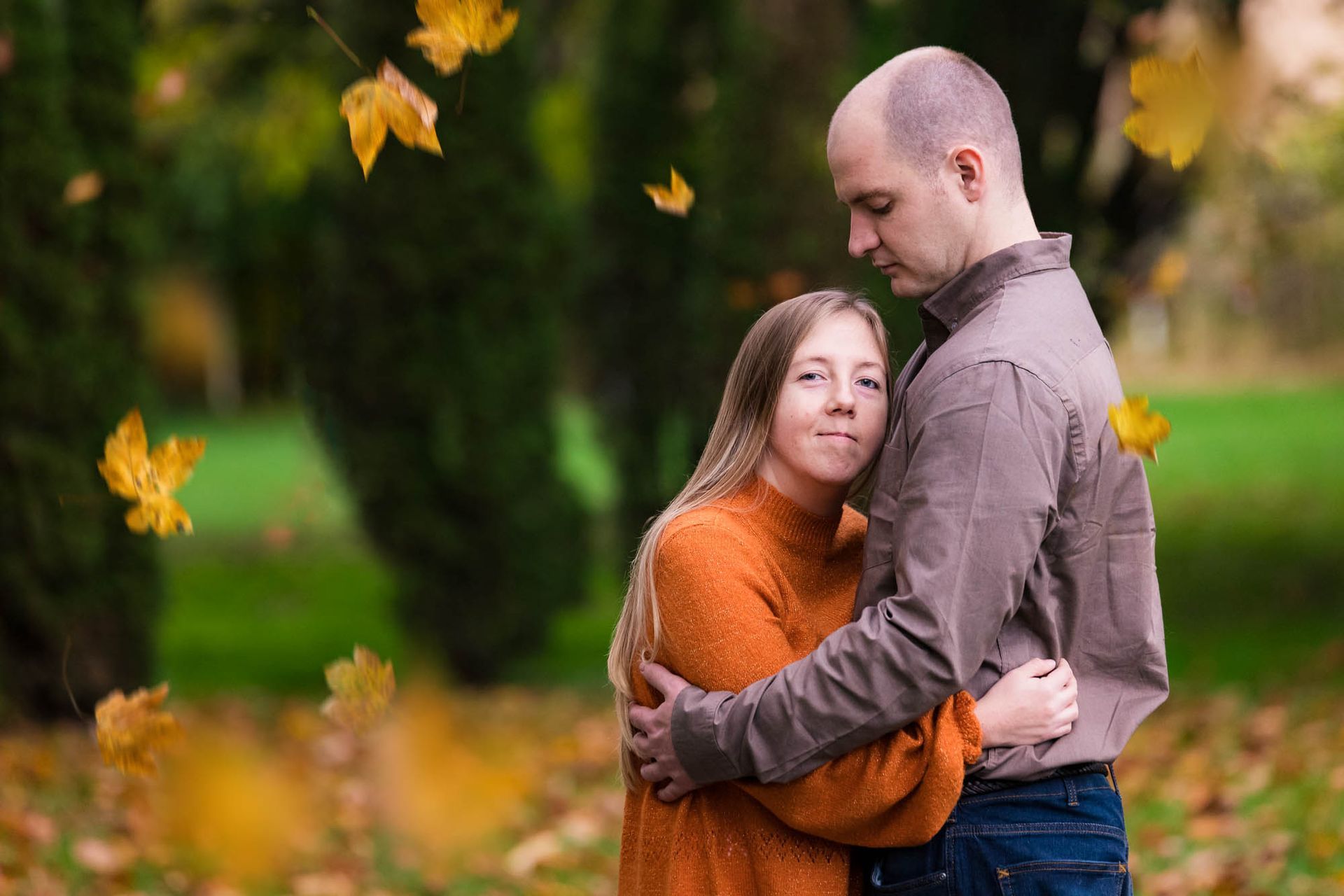 A man and a woman are hugging each other in a park.