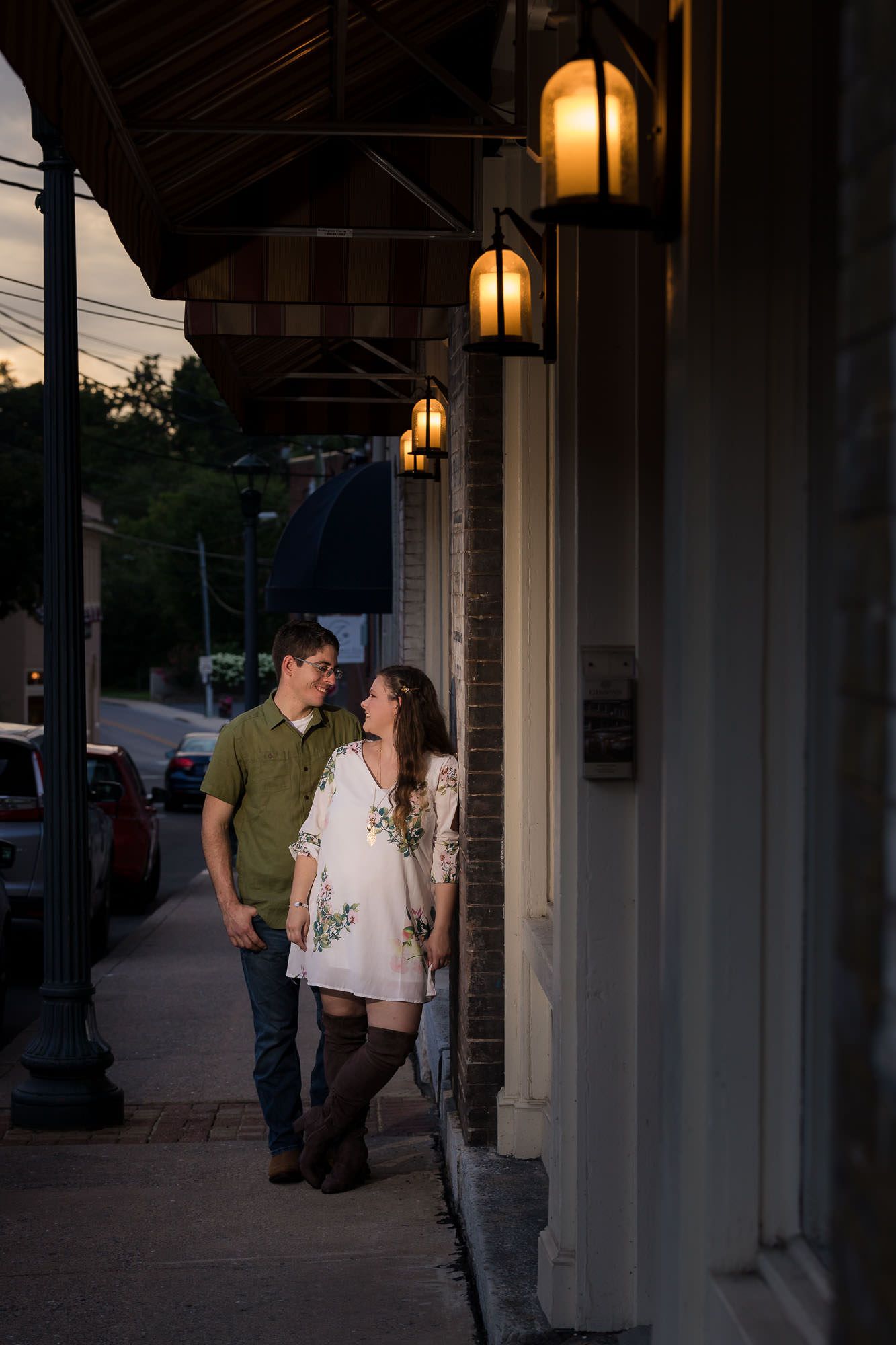 A man and a woman are standing next to each other on a sidewalk in front of a building.