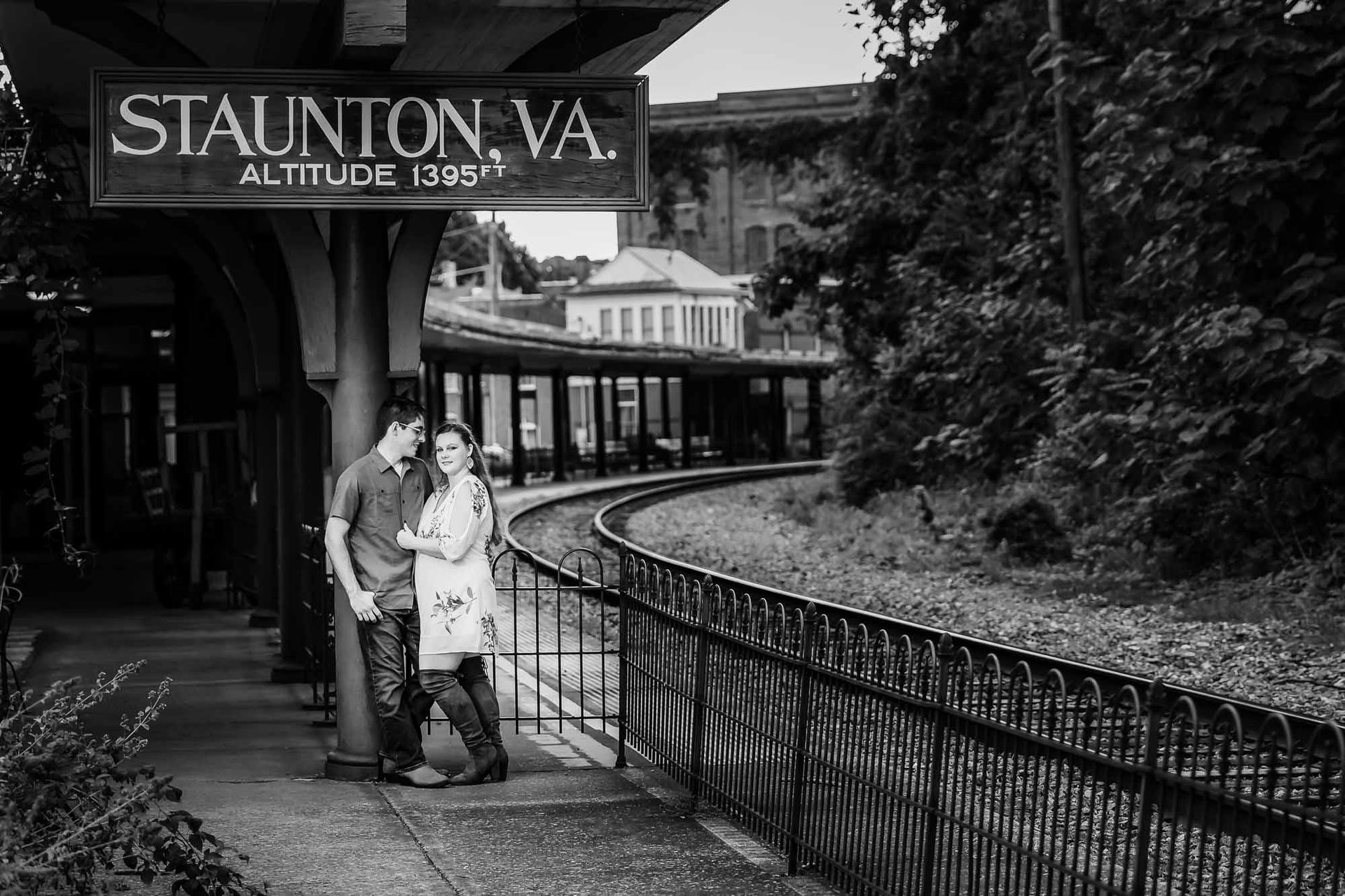 A black and white photo of a man and woman standing next to a train track.