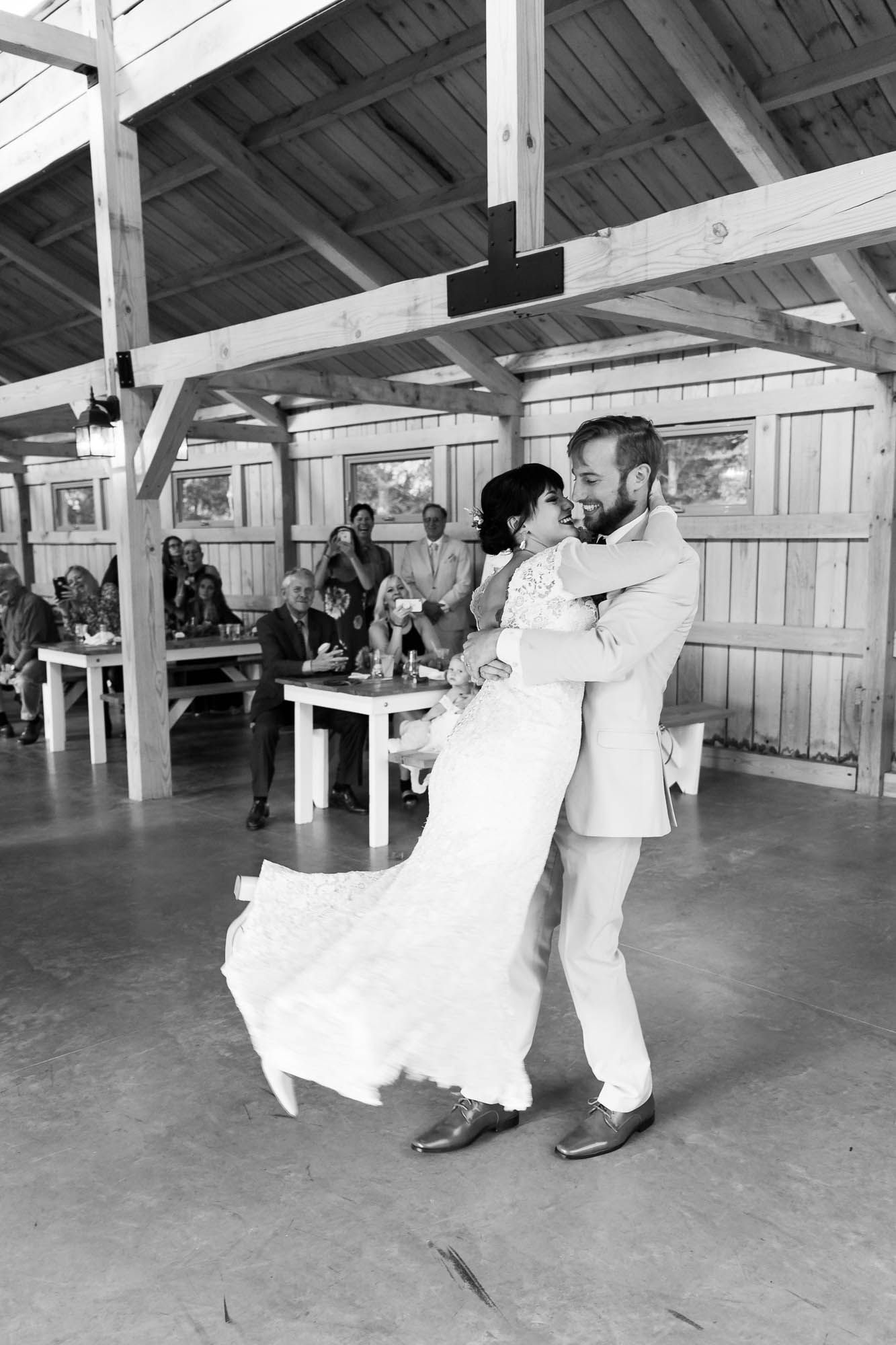 A black and white photo of a bride and groom dancing at their wedding reception.