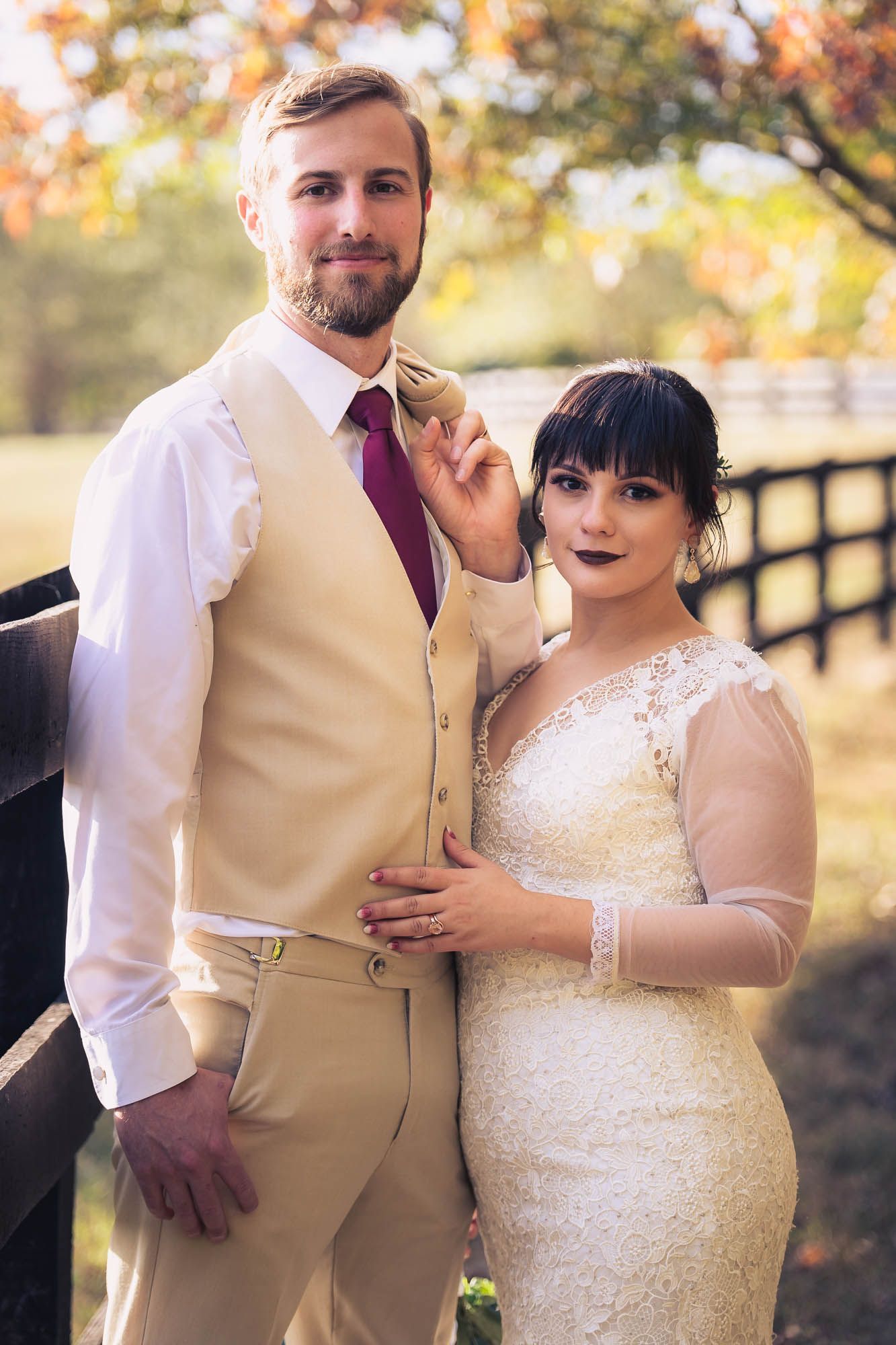 A bride and groom are posing for a picture in front of a fence.