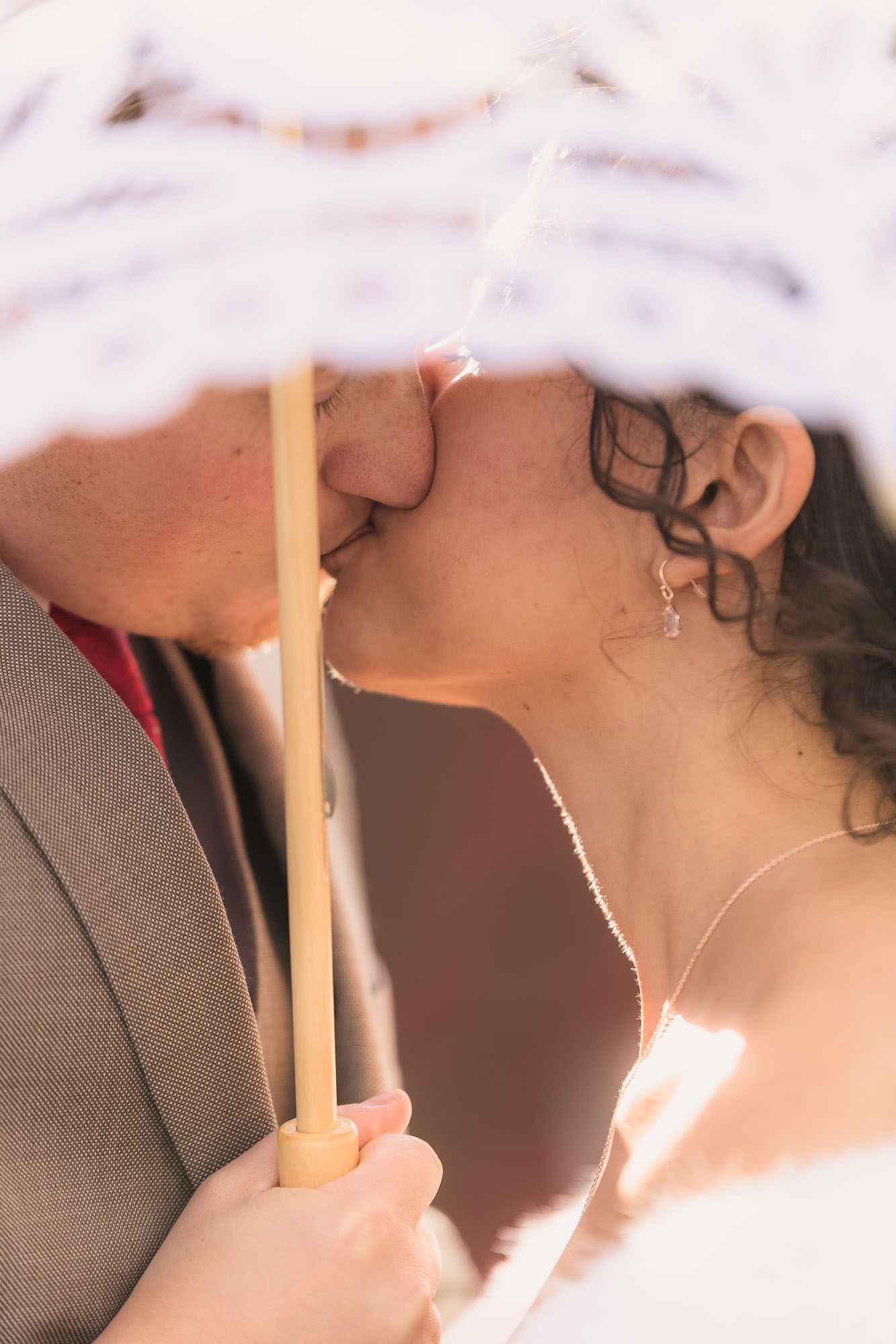 A man and a woman are kissing under an umbrella.