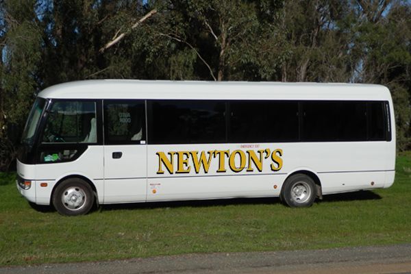 A white newton 's bus is parked in the grass