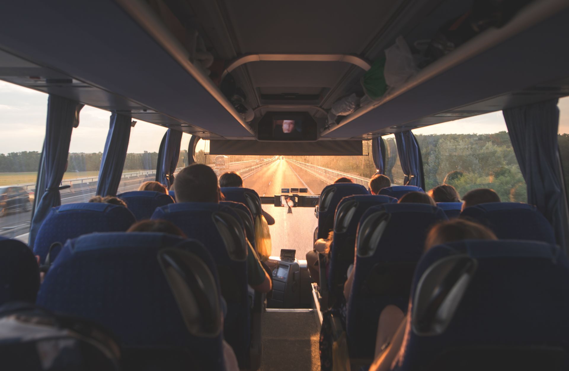 A coach charter with people going on the road in the evening at sunset.