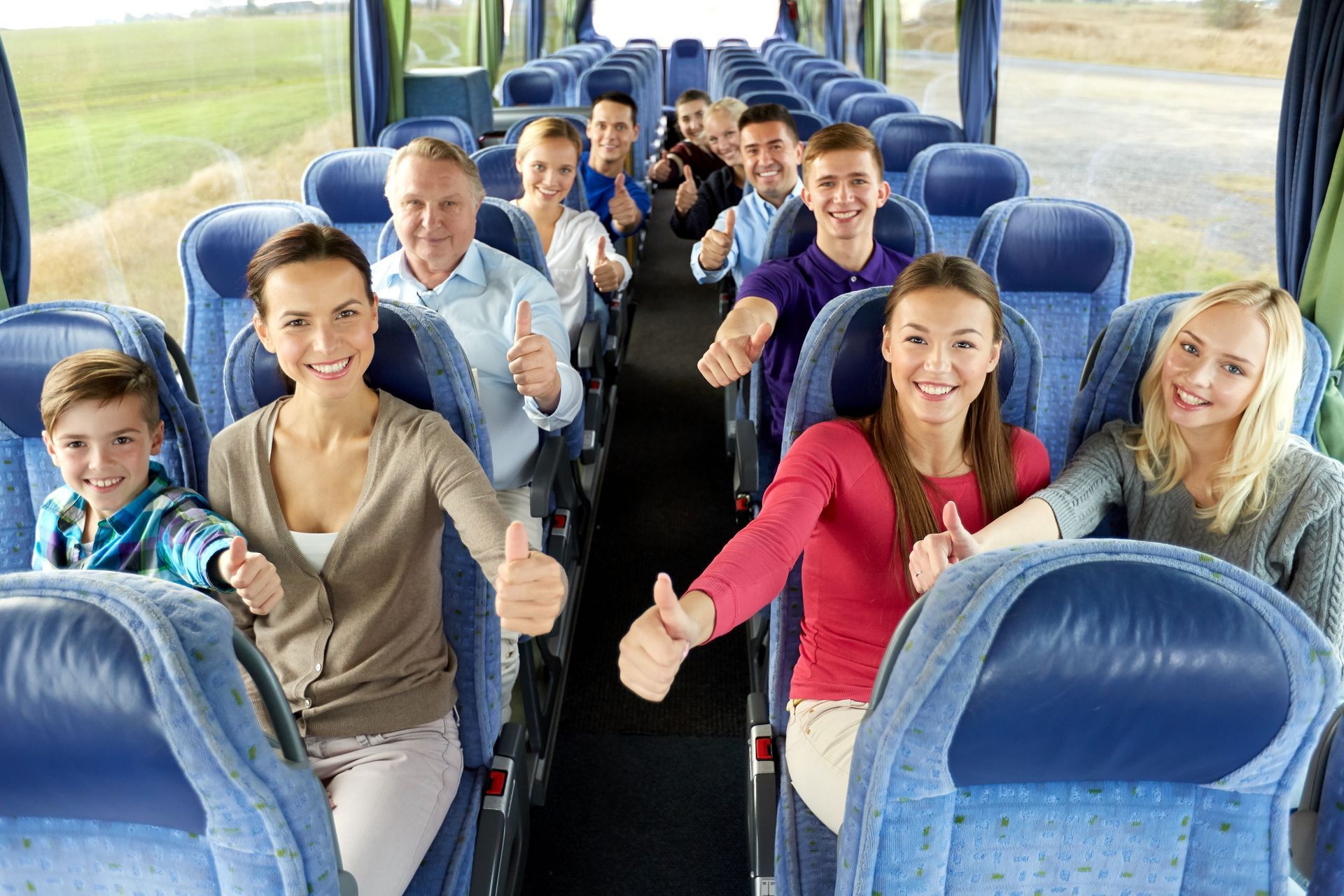 A group of happy passengers travelling by bus and showing thumbs up.