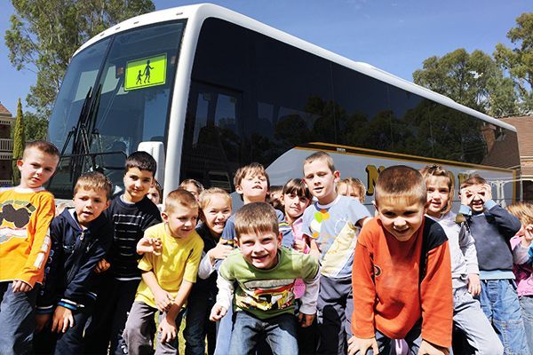 A group of children are posing for a picture in front of a school bus
