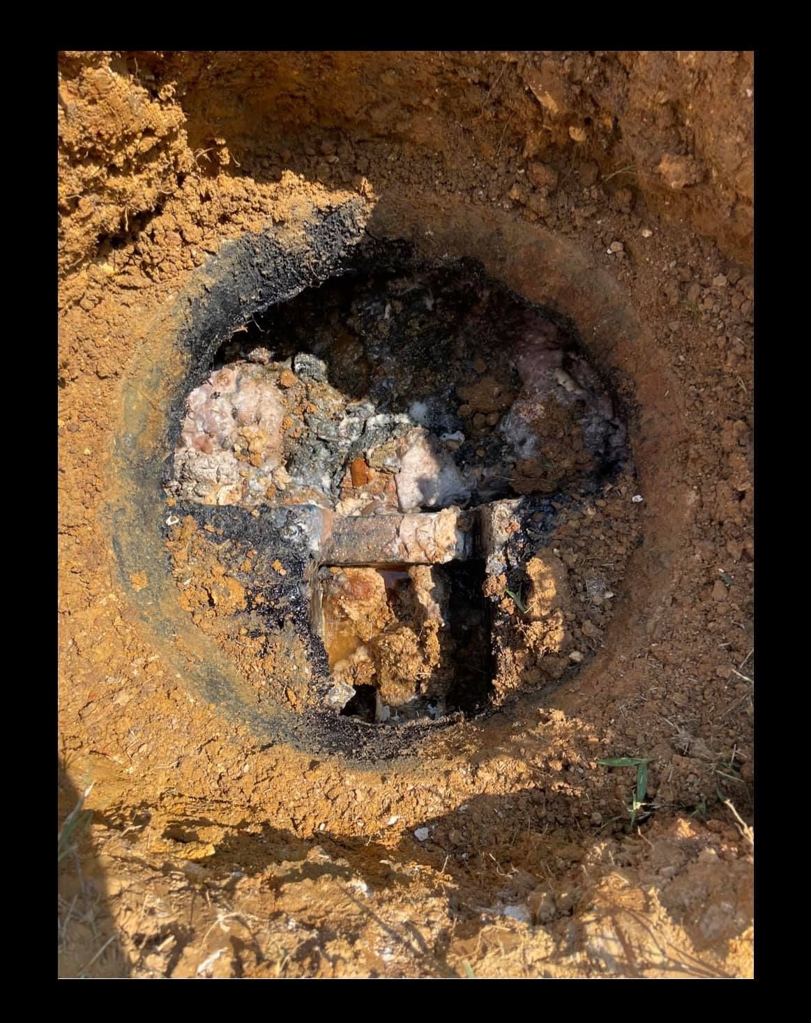 A close up of a hole in the septic tank ground filled with dirt.