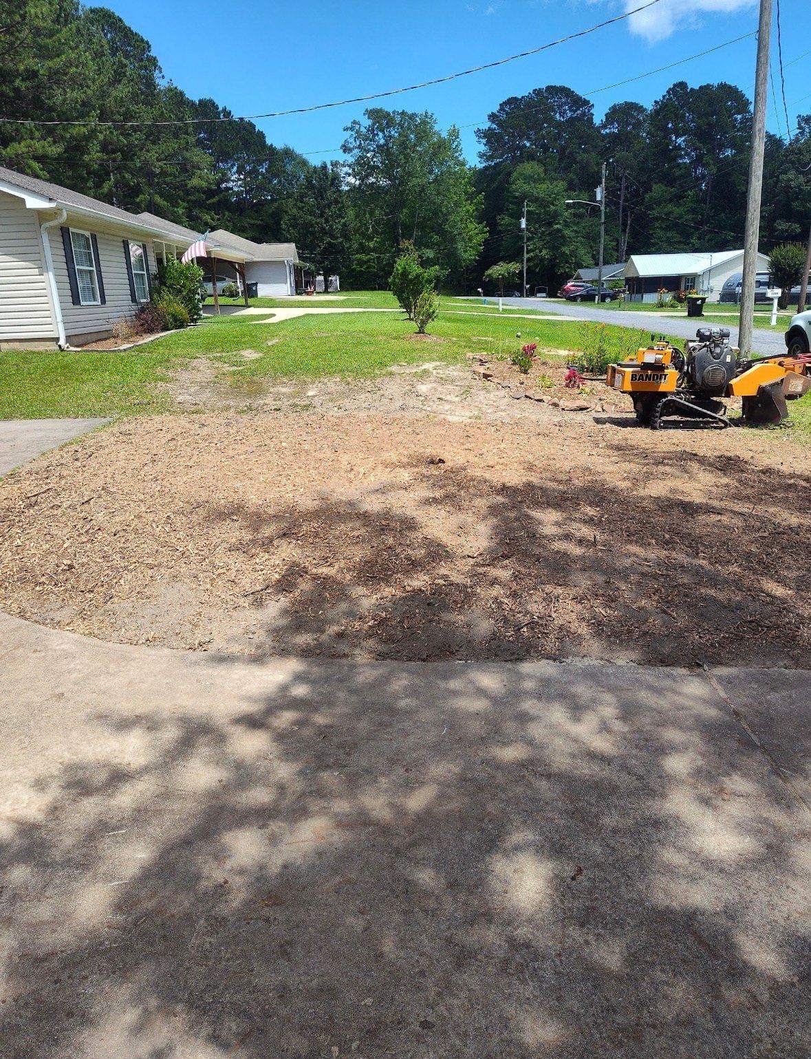 Stump grinder on a pile of wood chips in a yard. Sunny day, residential setting.