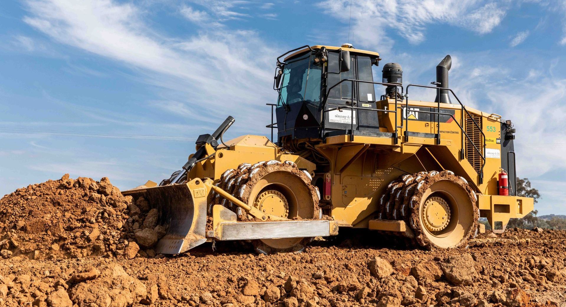 Two construction vehicles are working on a road.