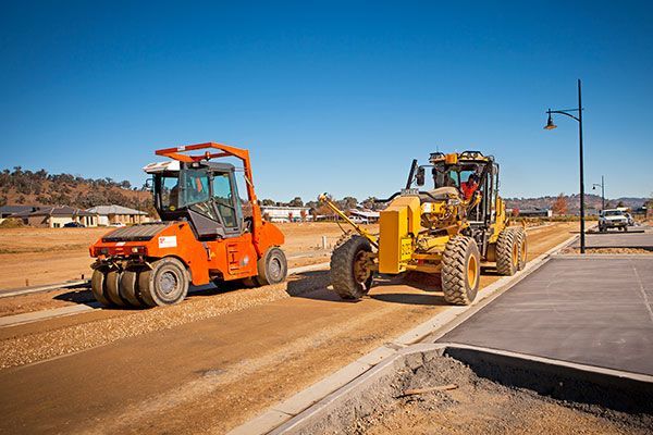 Two construction vehicles are driving down a road.