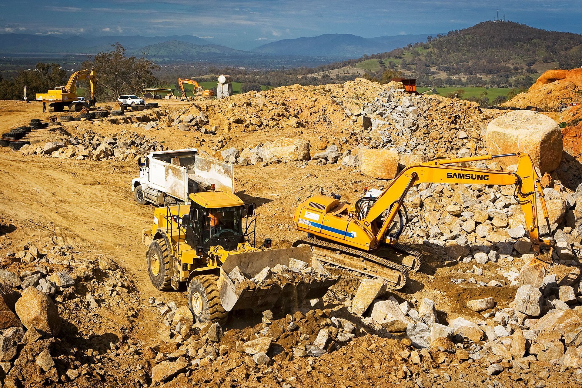 A large yellow excavator is working on a construction site.