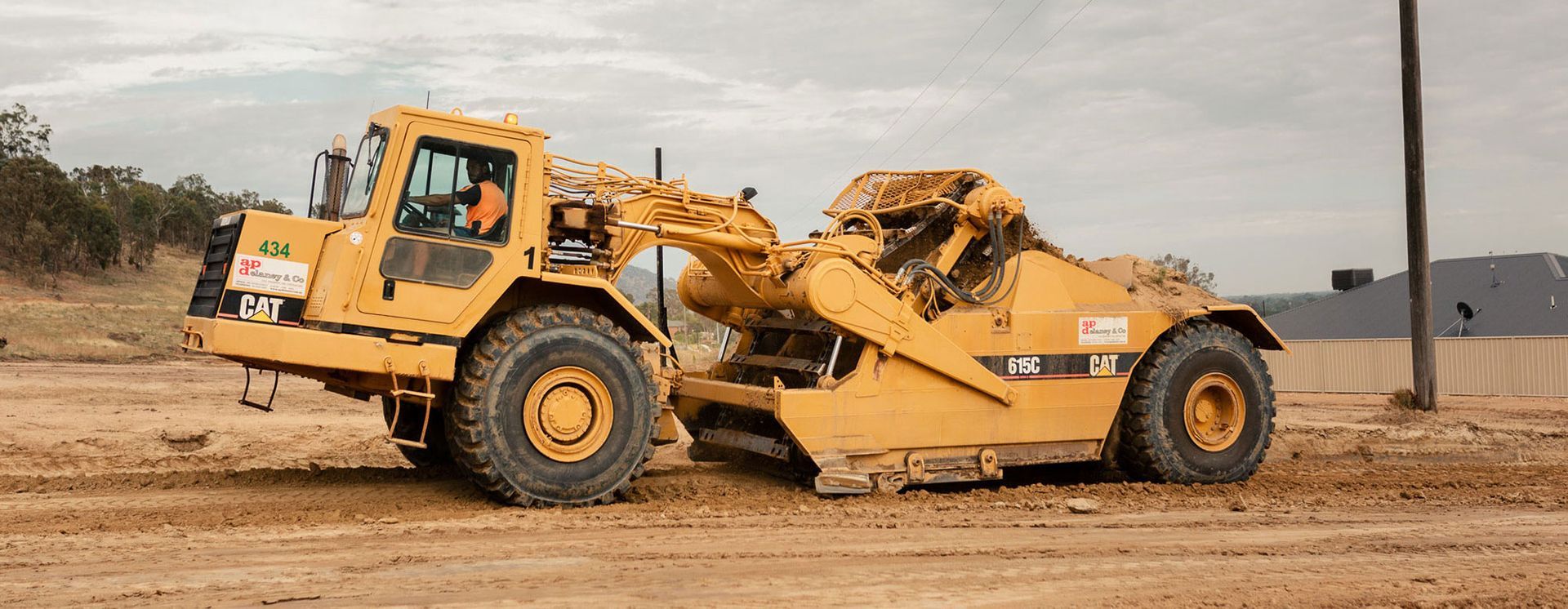 A yellow bulldozer is driving through a dirt field.