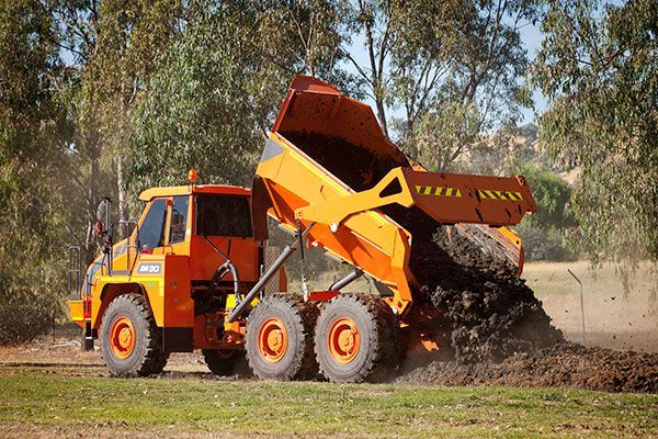 A dump truck is dumping dirt in a field.