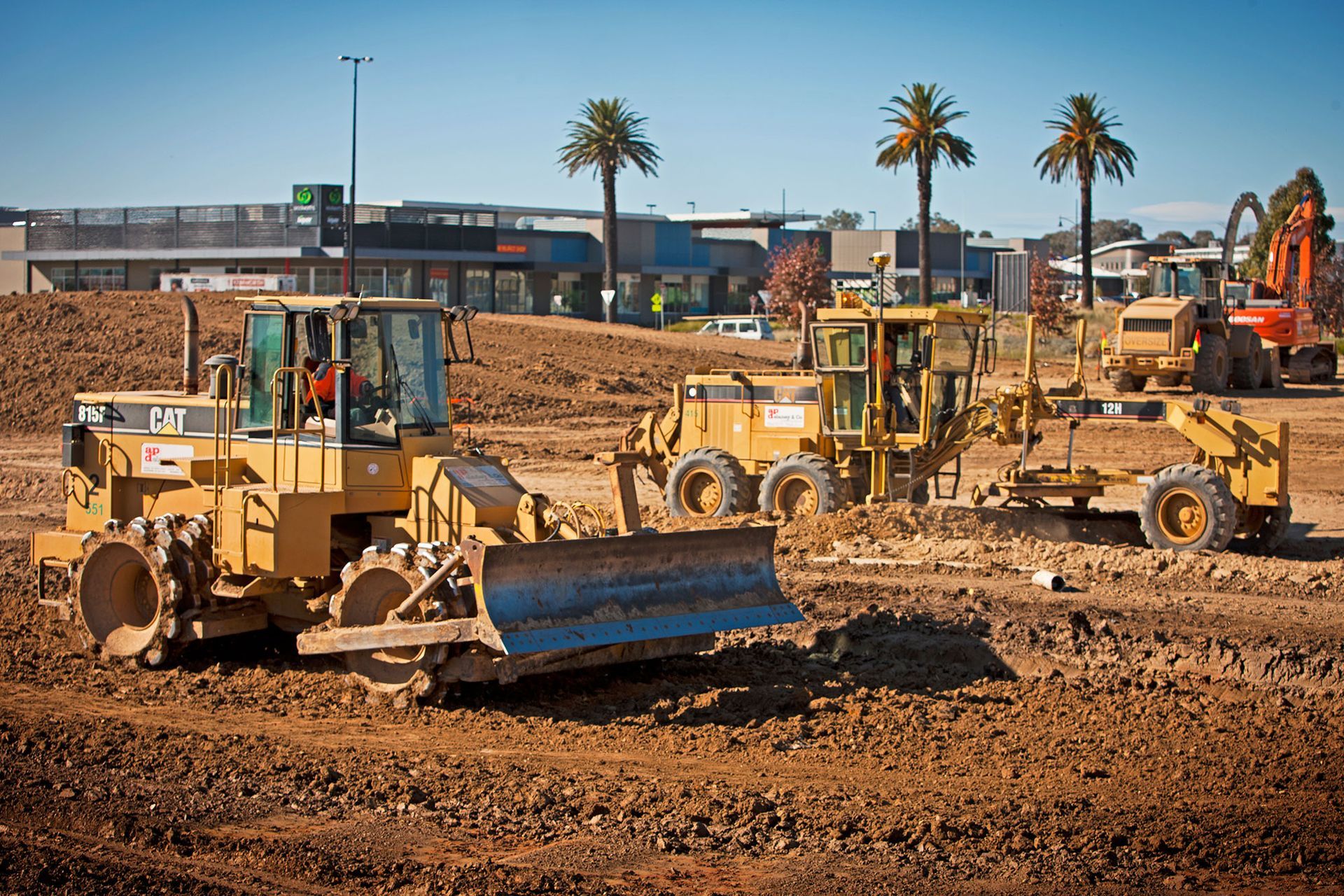 Several construction vehicles are parked in a dirt field