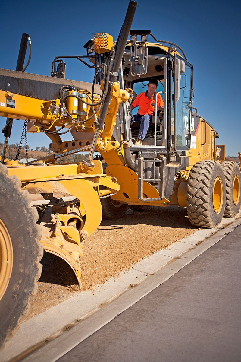 A man is driving a yellow tractor on a construction site.