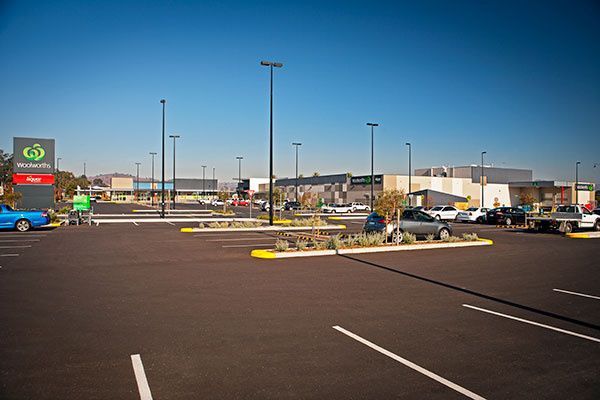 A parking lot with cars parked in front of a shopping center.