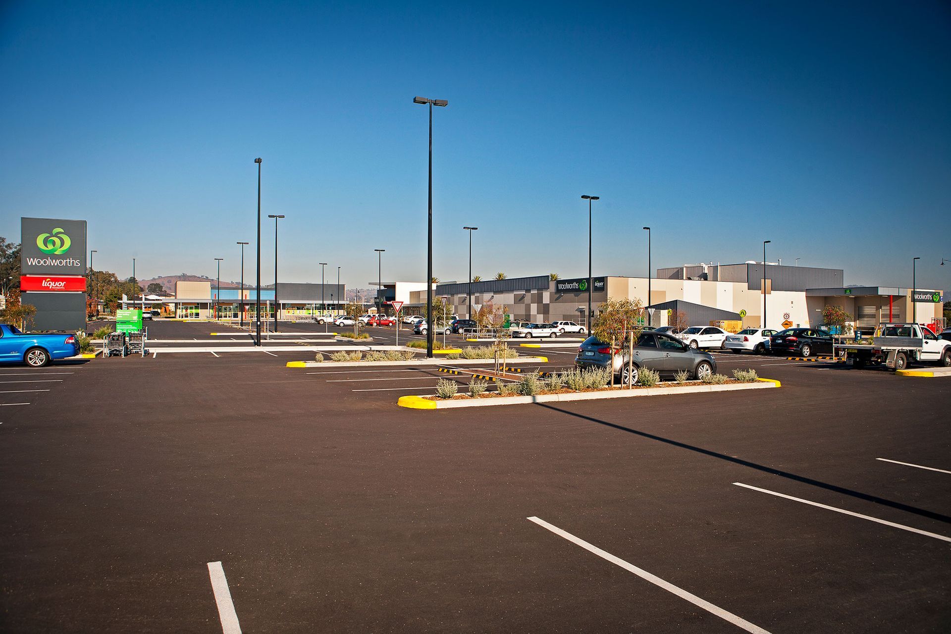 A parking lot with cars parked in front of a shopping center.