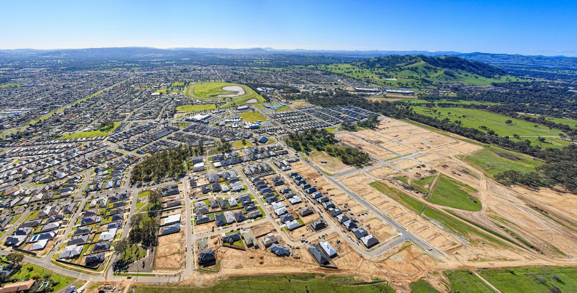 An aerial view of a residential area with a city in the background.