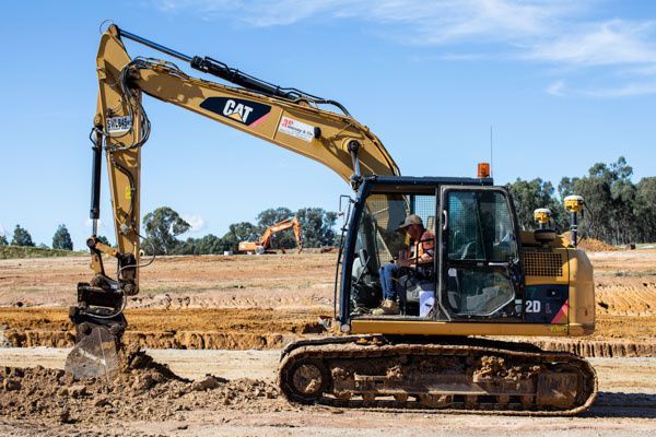 A yellow excavator is sitting on top of a dirt field.