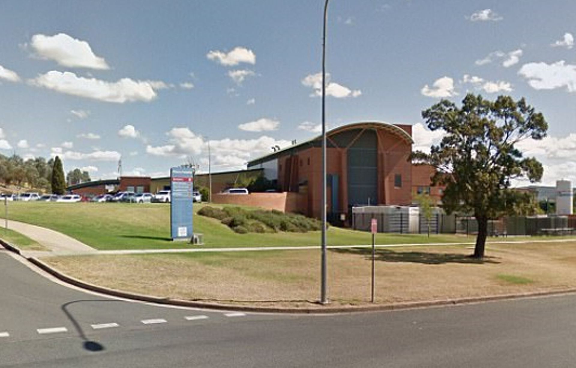 A large building is sitting on the side of a road next to a grassy field.