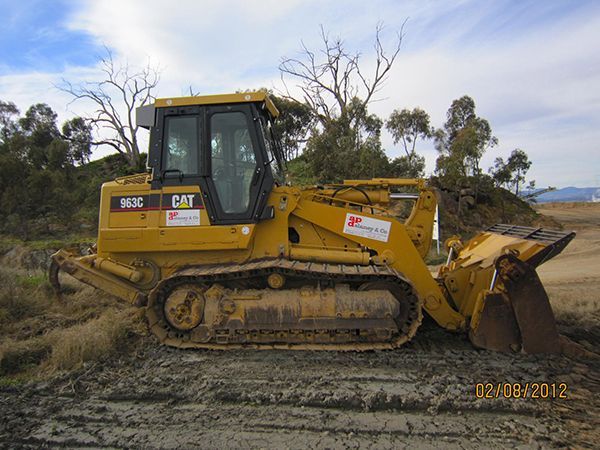 A yellow bulldozer is parked in the middle of a dirt field.