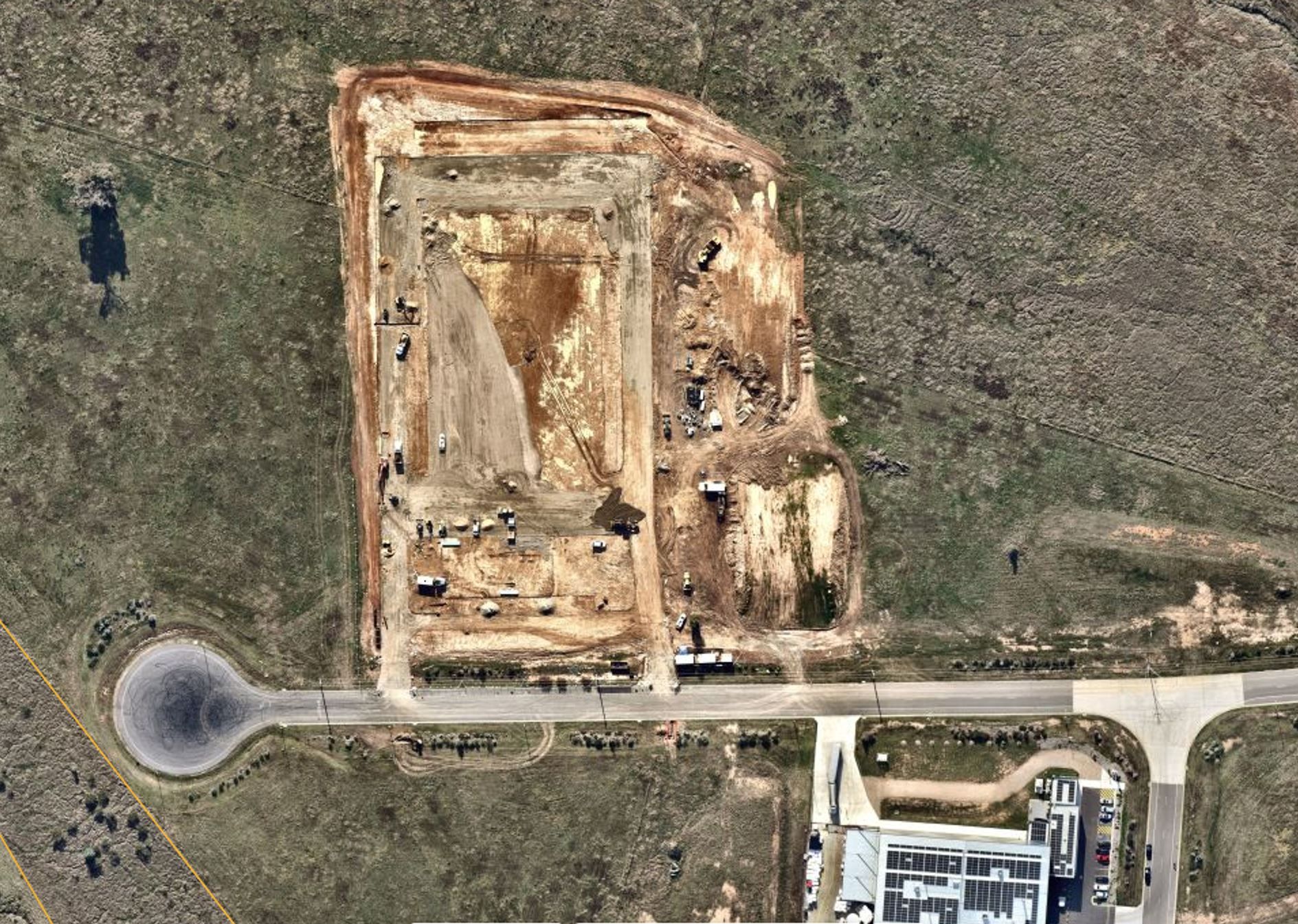 An aerial view of a construction site with a roundabout in the middle