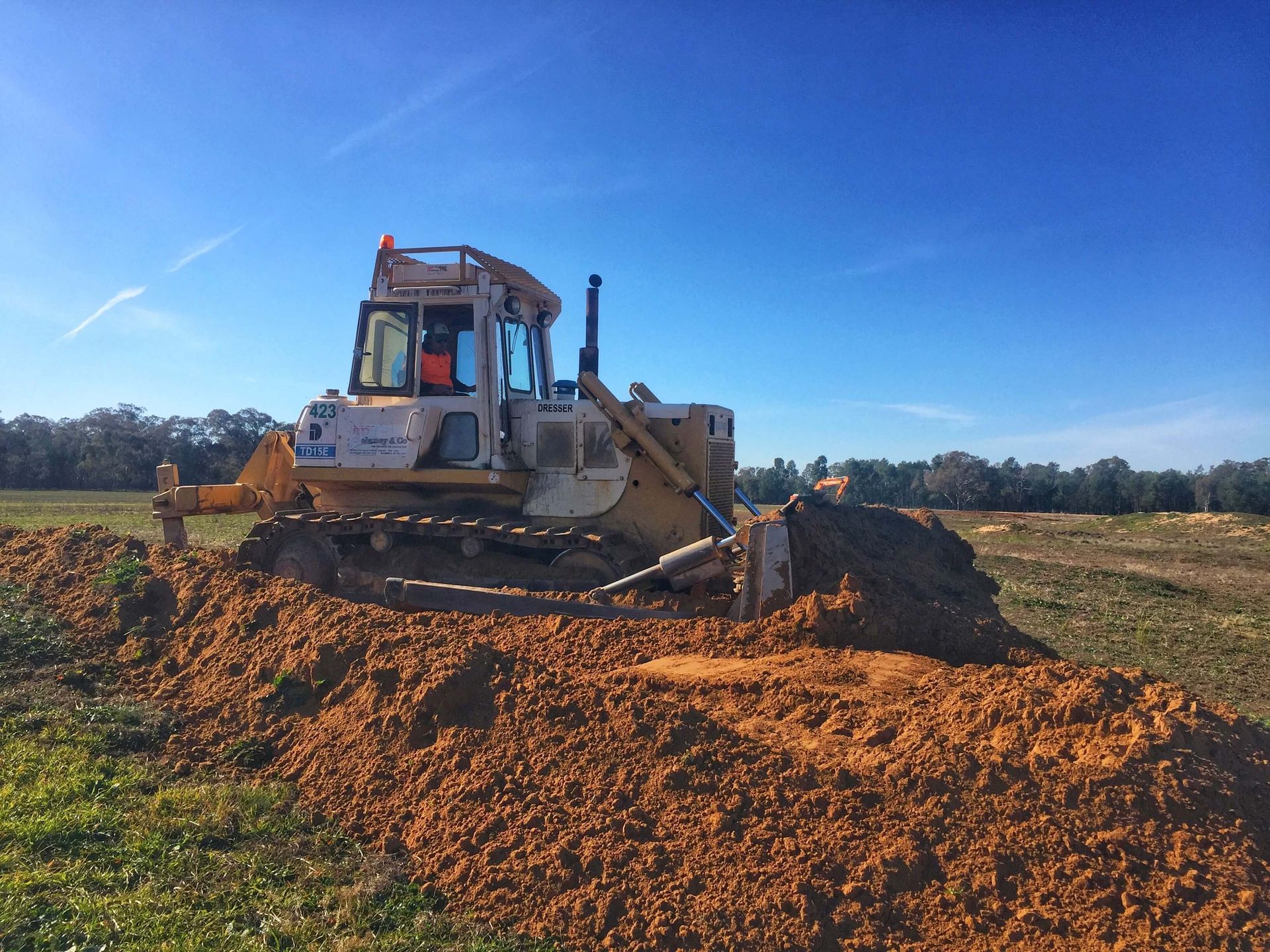 A bulldozer is moving dirt in a field.