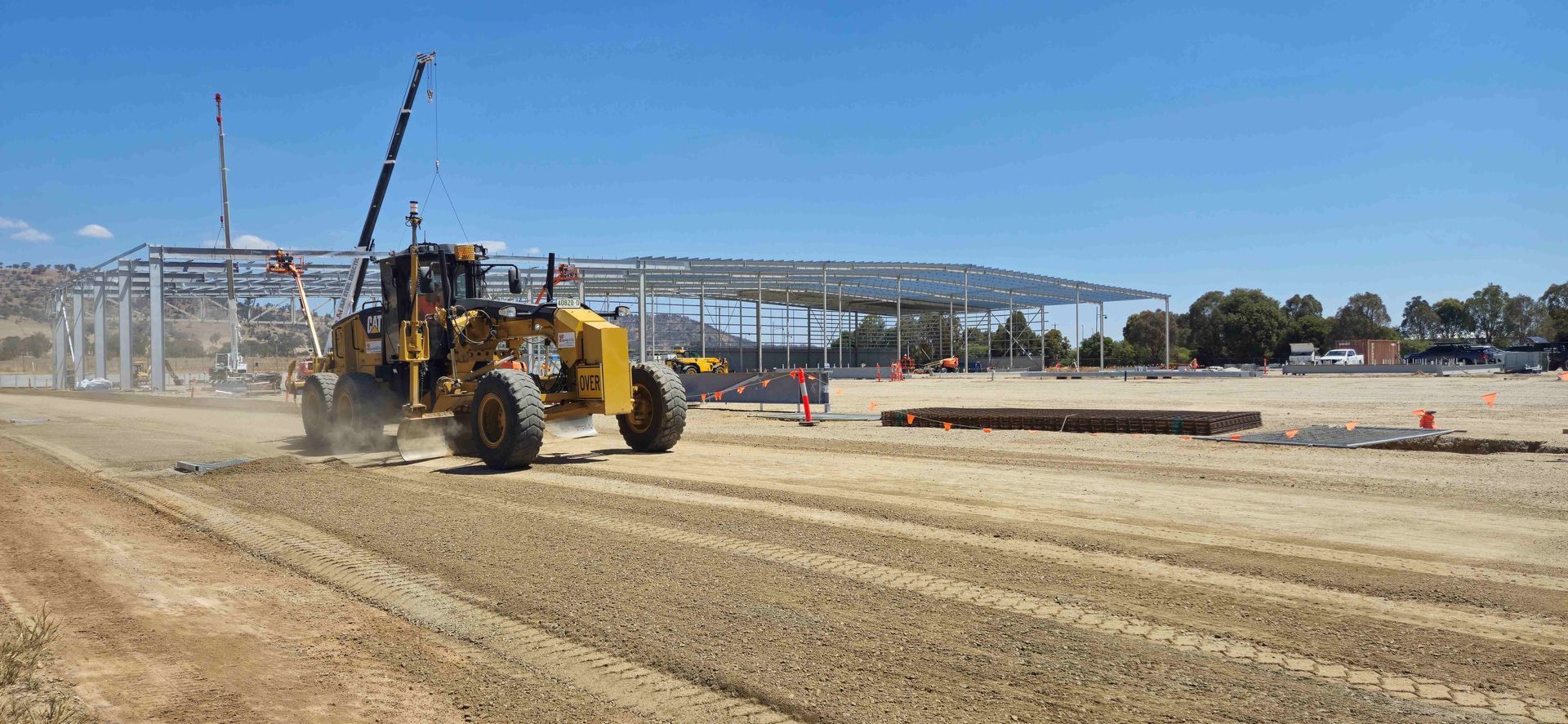 A dump truck is driving down a dirt road next to a trailer.