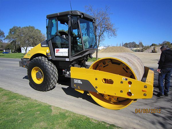 A yellow and black road roller is parked on the side of the road