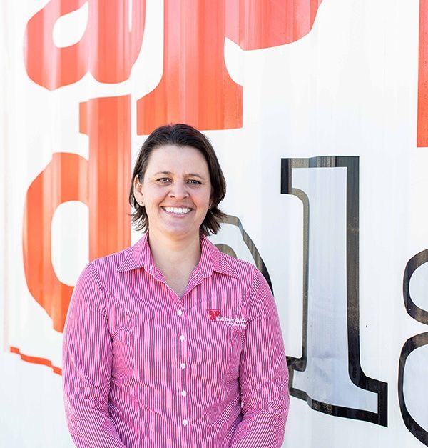 An older man wearing a red sweater and a blue shirt is smiling for the camera.