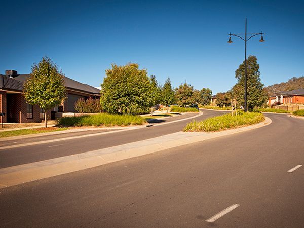 A curvy road with a street light on the side of it in a residential area.