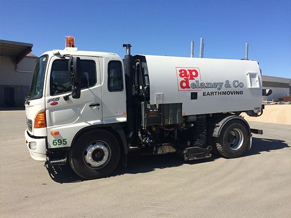 A white street sweeper truck is parked in a parking lot.