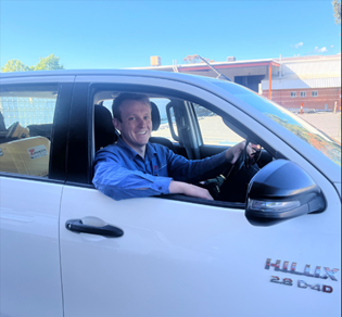 A woman in a pink striped shirt is smiling in front of a wall with the number 1 painted on it
