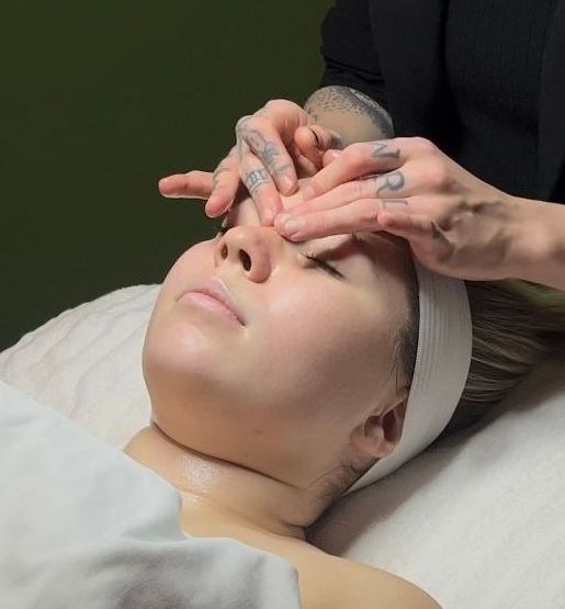 A woman is laying on a bed getting a massage on her face