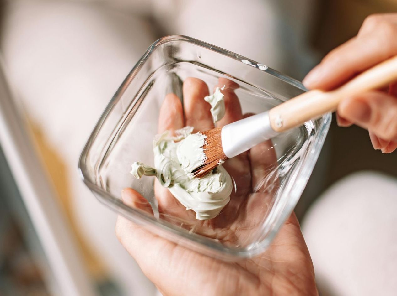 A person is applying a mask to their face with a brush.