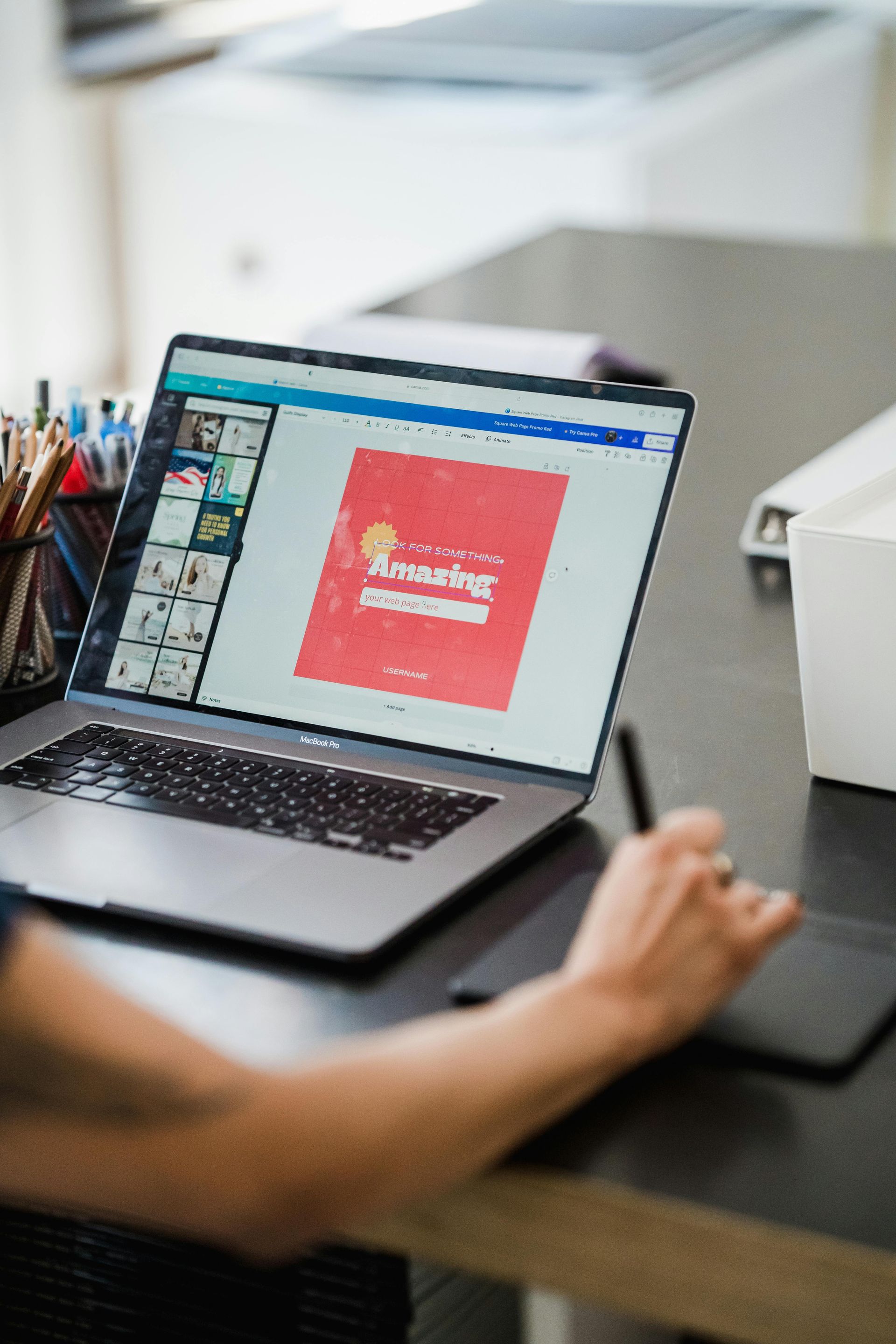 Person working on a laptop displaying a red design on a desk