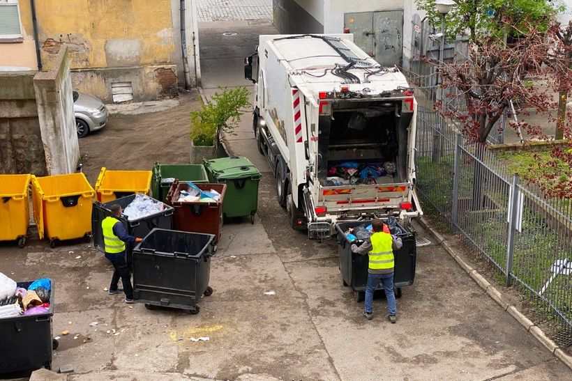 People loading a dumpster truck with junk