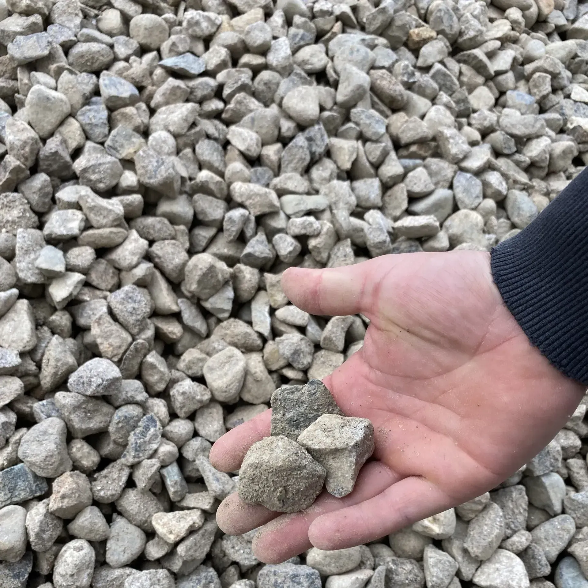 A person is holding a pile of gravel in their hand
