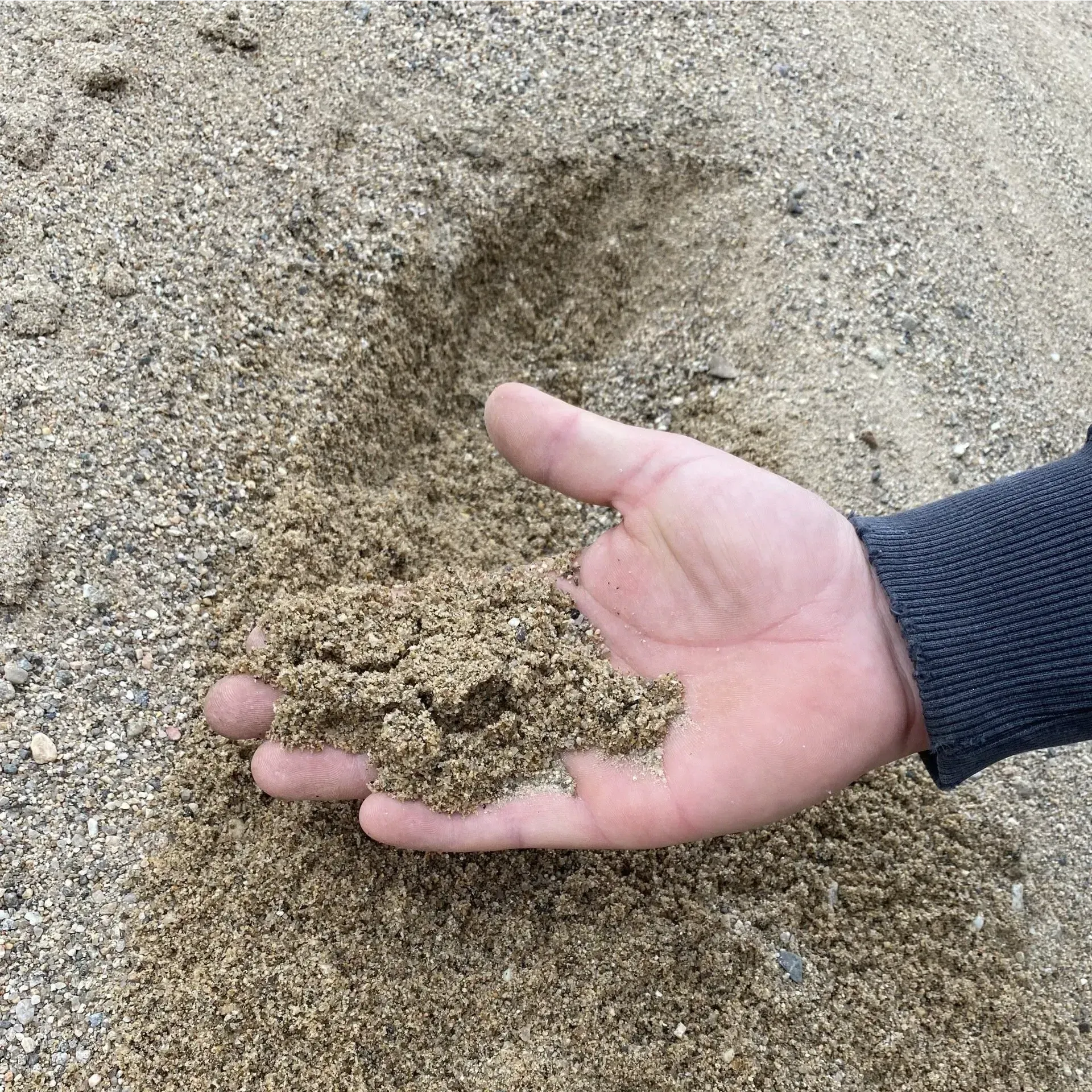 A red and white excavator is driving down a dirt road.