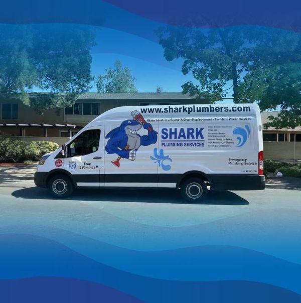 A shark plumbing service van is parked on the side of the road