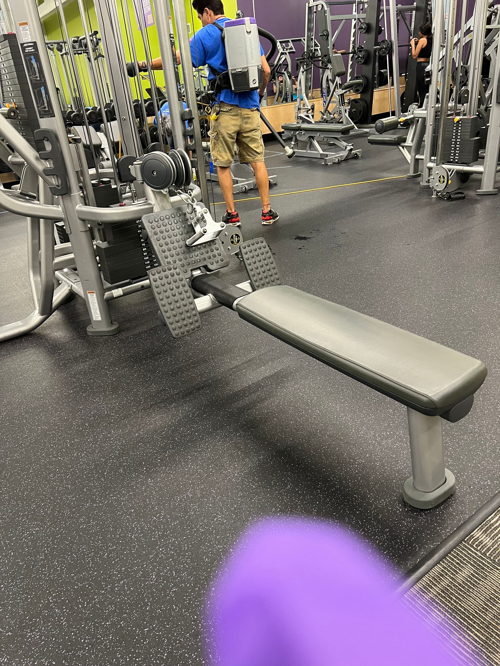 A man is standing next to a bench in a gym.