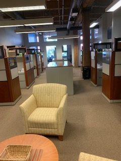 There are many cubicles in this office with a chair and a table.