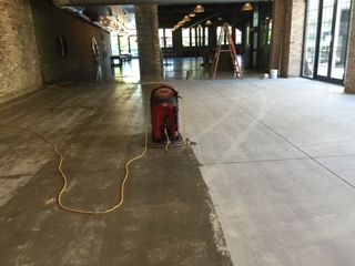 A person is using a vacuum cleaner to clean a concrete floor.