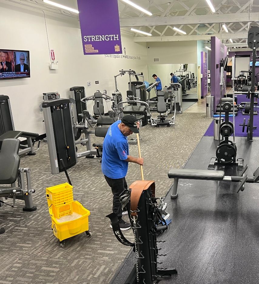 A man is cleaning a gym with a sign that says strength