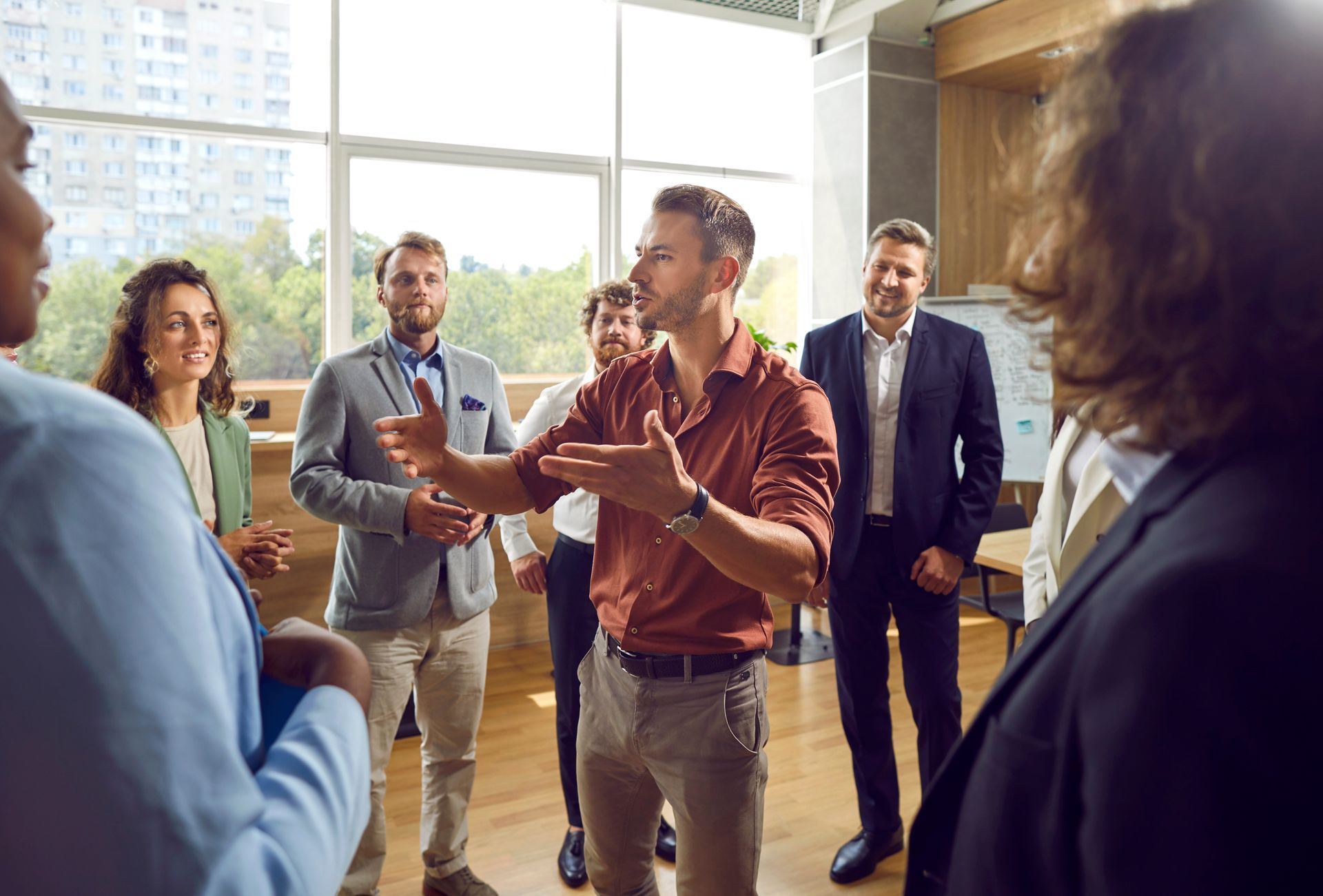 Group of people in office setting, man speaking with hands raised. Group of people in office setting, man speaking with hands raised.