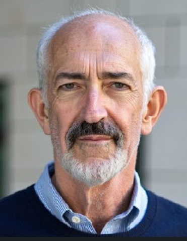 Group of people collaborating around a table covered in a sketch and sticky notes, smiling and pointing.